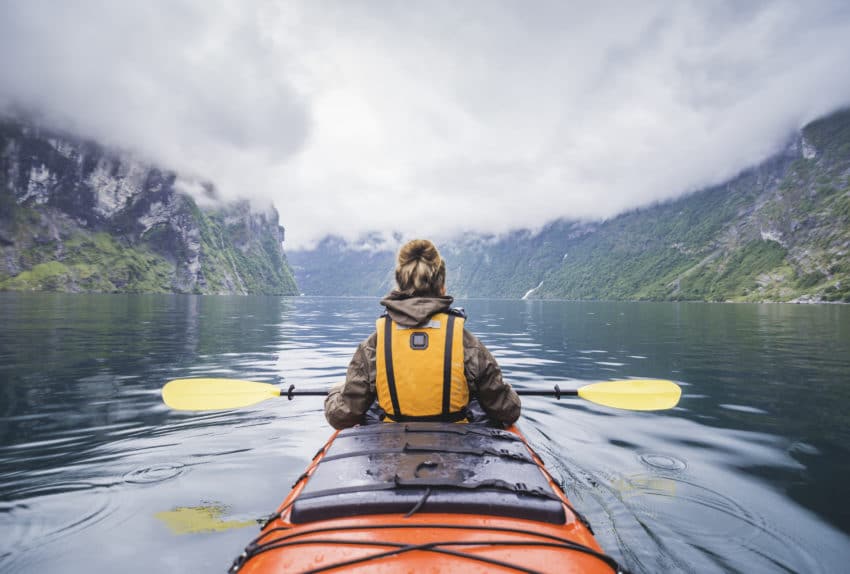 Woman kayaking in fjord in Norway.