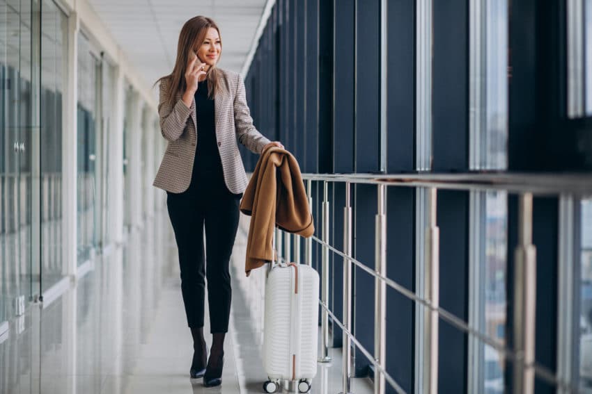 Business woman in terminal with travel bag talking on phone