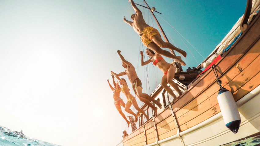 Friends jumping off a boat into tropical waters