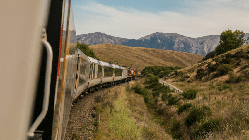 Passenger train passing through field overlooking mountains