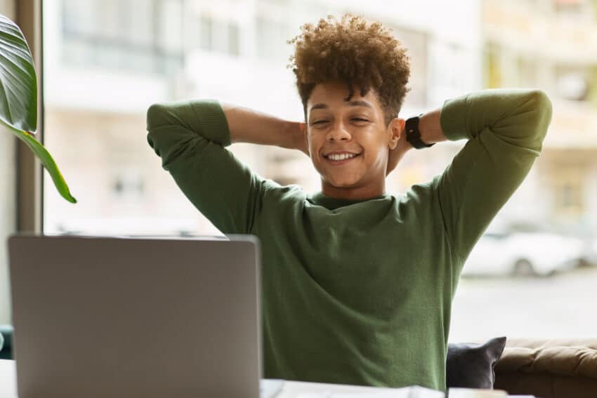 Happy young black guy businessman looking at laptop screen